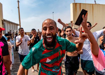 Migrants returning toward Morocco near the border fence in Ceuta as security forces stand nearby.