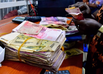 A currency trader watches exchange-rate screens displaying several African currencies.
